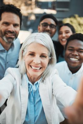 Shot of a mature businesswoman standing outside with her colleagues and taking selfies, employment law
