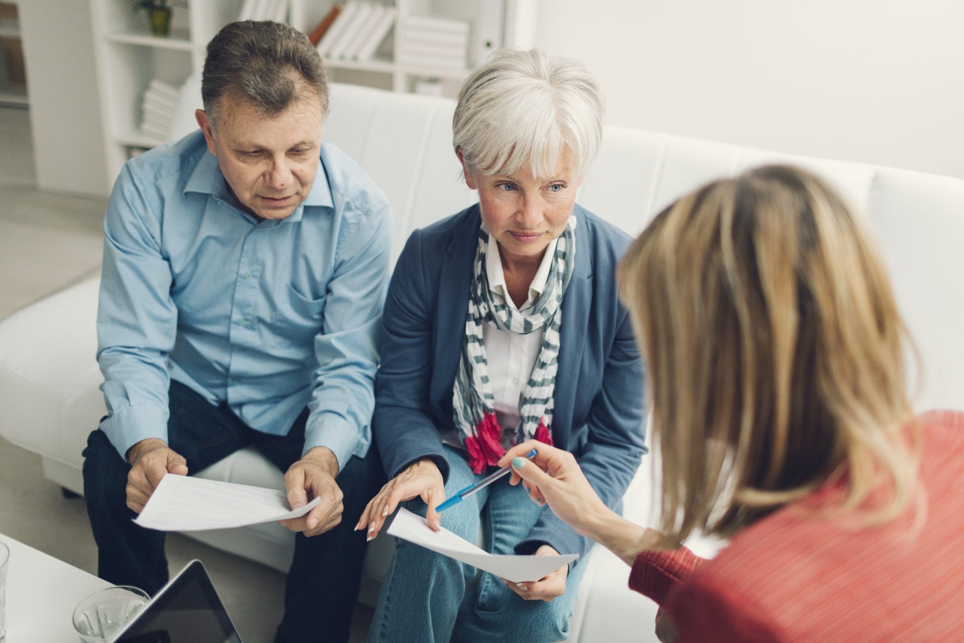 Olivia Wann Law Office, Elder Law. Mature Couple Meeting with Financial Advisor, who is pointing with pencil to some contract details.