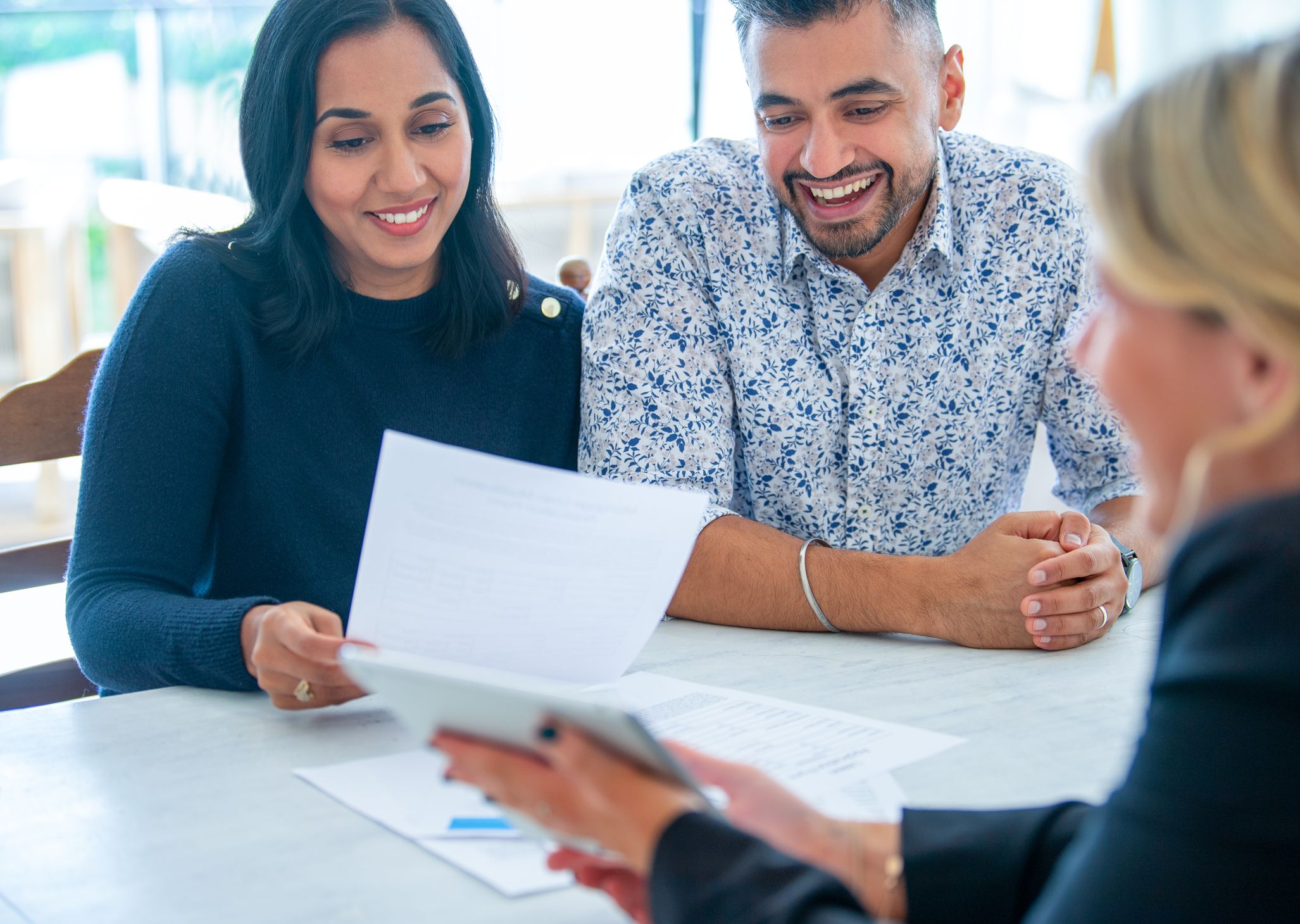 Olivia Wann Law Office, Legal Services. A couple meeting with financial advisor for business planning They are sitting at a table at a paper work document a digital tablet presentation.